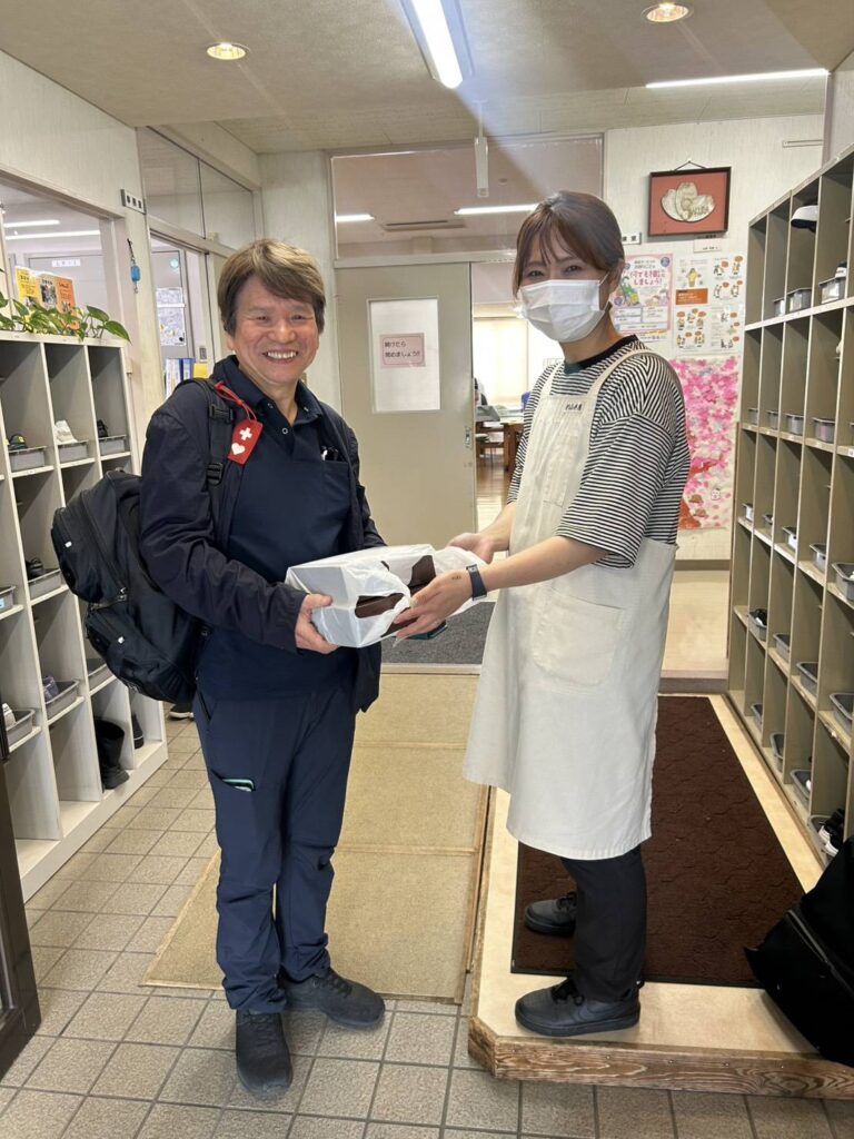 Delivery person hands a wrapped box to a staff member at an indoor reception area.