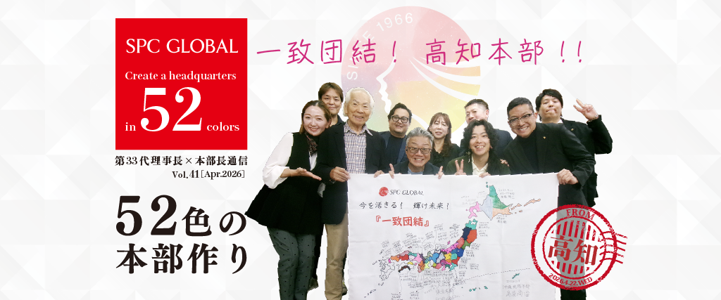 Group of diverse people posing with a banner featuring a map of Japan, a red stamp, and the SPC Global logo on a patterned backdrop.